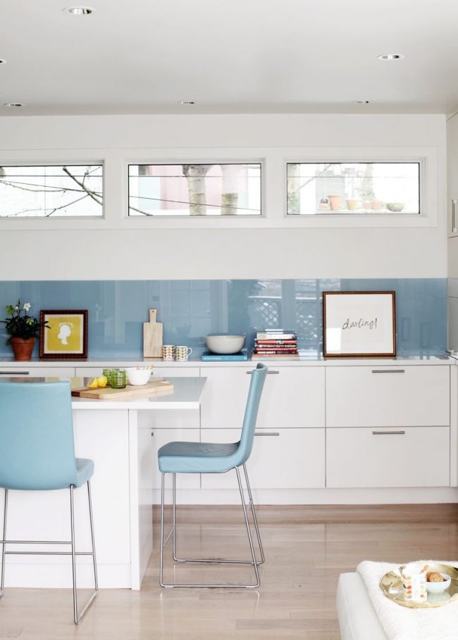 Бело голубая кухня: узкий голубой фартук и голубые стулья удачно освежают белый интерьер кухни