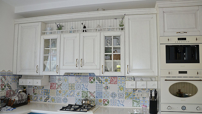 Фартук, выложенный мелкой плиткой с орнаментом или цветочными мотивами – отличный вариант для подобных кухонь