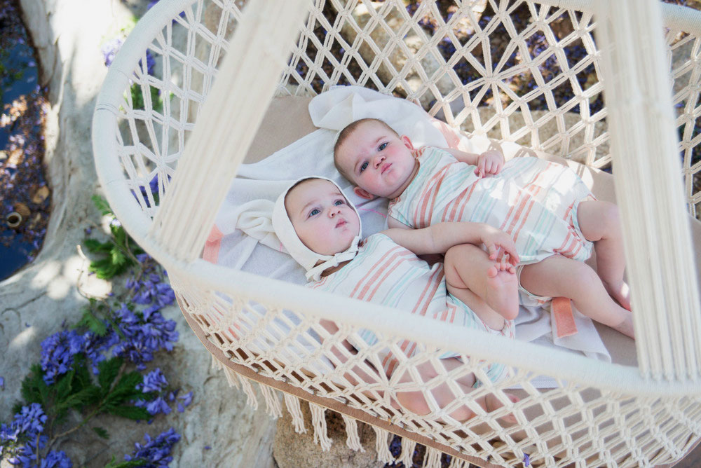 Два младенца в плетенной подвесной колыбели на улице