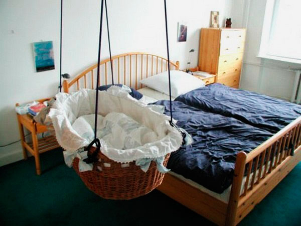 Плетенная колыбель подвешенная к потолку рядом с родительской кроватью