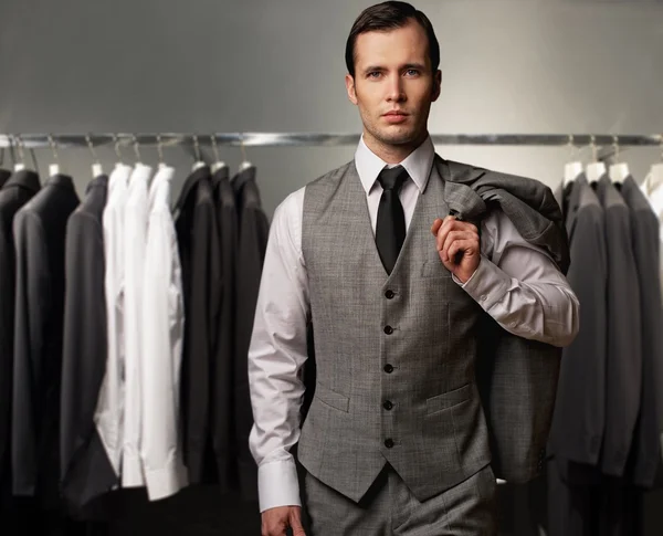 Businessman in classic vest against row of suits in shop — стоковое фото