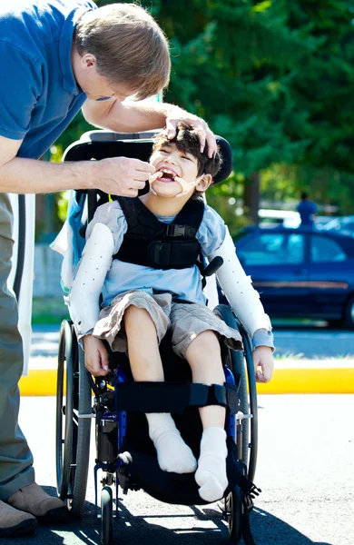 Отец помогает отключить ребенка в коляске — стоковое фото