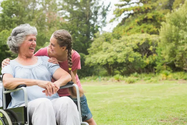 Внучка обнимать бабушку в инвалидной коляске — стоковое фото
