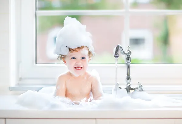 Девочка с большие голубые глаза, играя в ванне — стоковое фото