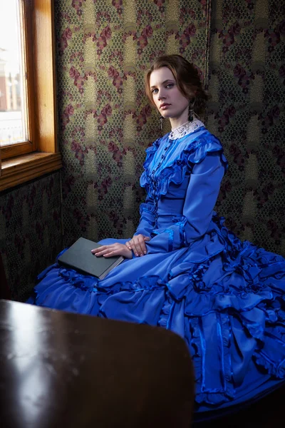 Молодая женщина в синий старинные платья, сидя с книгой в купе — стоковое фото