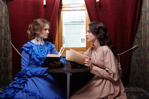 Две сестры в ретро платье, читать книги в купе поезда — стоковое фото