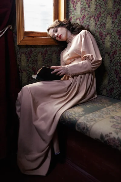 Молодая женщина в бежевый винтажное платье чтения начала XX века — стоковое фото