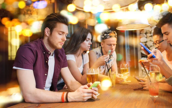 Друзья с смартфонов и напитки в баре — стоковое фото