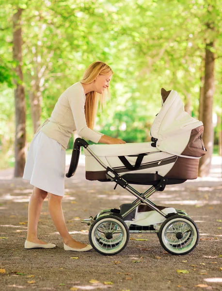 Счастливая мать с коляски в парке — стоковое фото