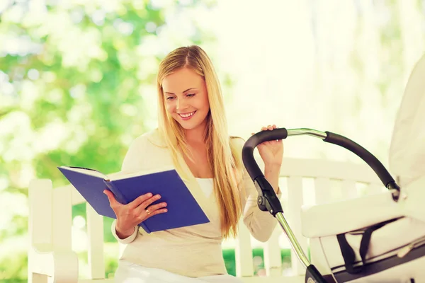 Счастливая мать с книгой и коляска в парке — стоковое фото