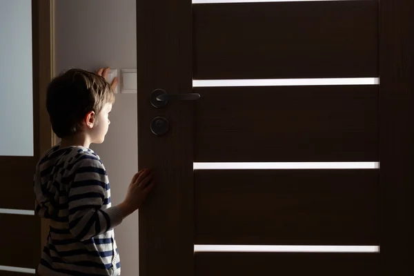 Маленький мальчик открывает дверь в комнату — стоковое фото