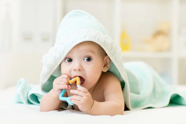 Ребенок с Teether во рту под купальным полотенцем в детском саду — стоковое фото