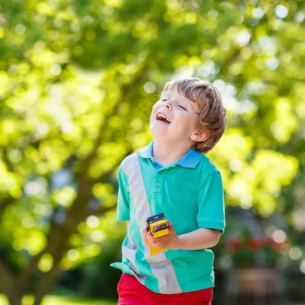 Маленький ребенок мальчик играет с игрушкой автомобилей, на открытом воздухе — стоковое фото