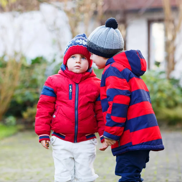 Два мальчика родственный красной куртки и Шапки зимние говорить t — стоковое фото