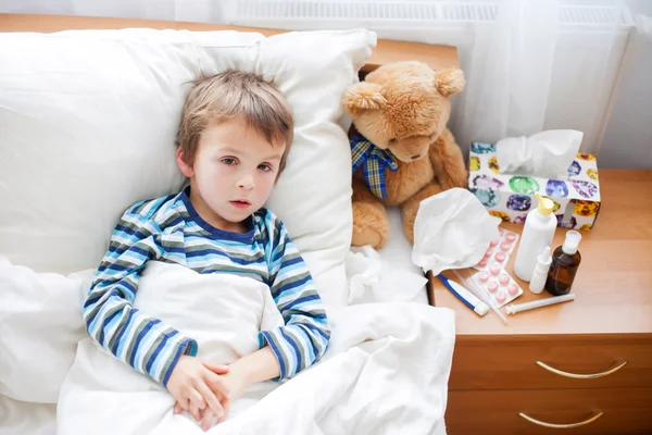 Больной ребенок мальчик, лежа в постели с лихорадкой, отдыхает — стоковое фото