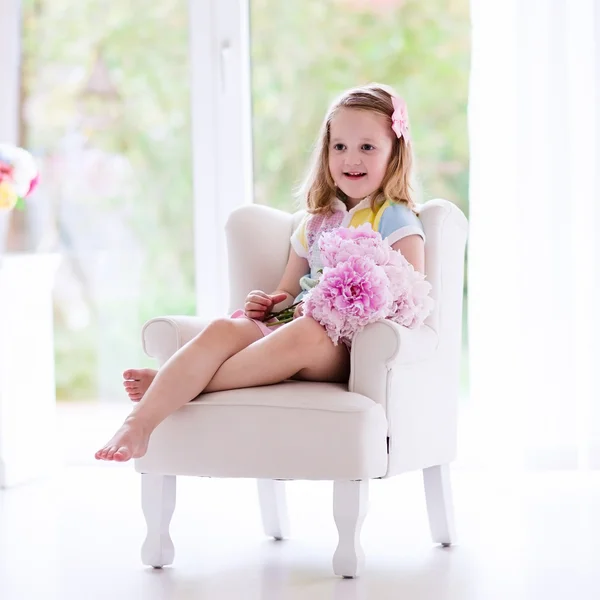 Маленькая девочка с цветами Пион в Белая спальня — стоковое фото