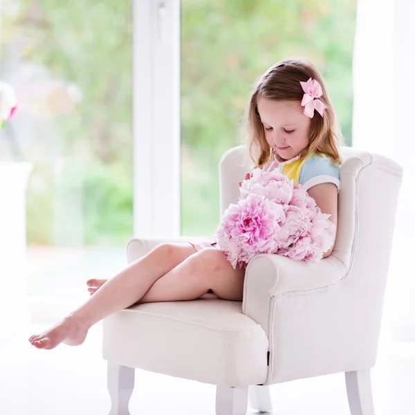 Маленькая девочка с цветами Пион в Белая спальня — стоковое фото
