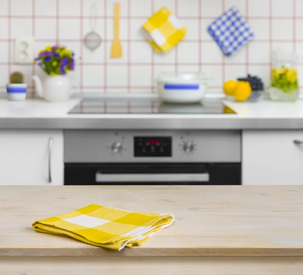 Деревянный стол с желтая салфетка на фоне кухни — стоковое фото