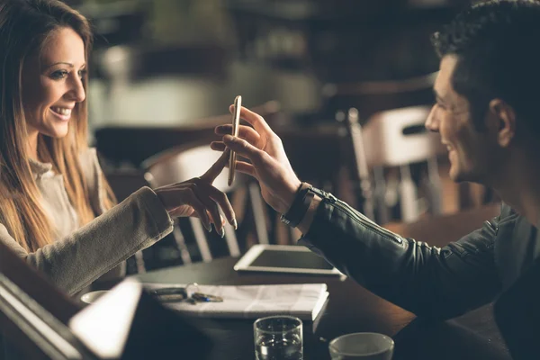 Модный пару в баре с помощью смарт-телефона — стоковое фото