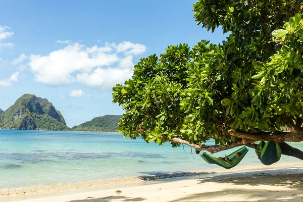 A man is reading a book in the hammock on the beach of the island of Palawan in the Philippines (El Nido) — стоковое фото