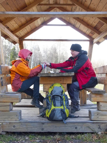 Туристы, сидя в деревянной беседке за столом и напиток — стоковое фото