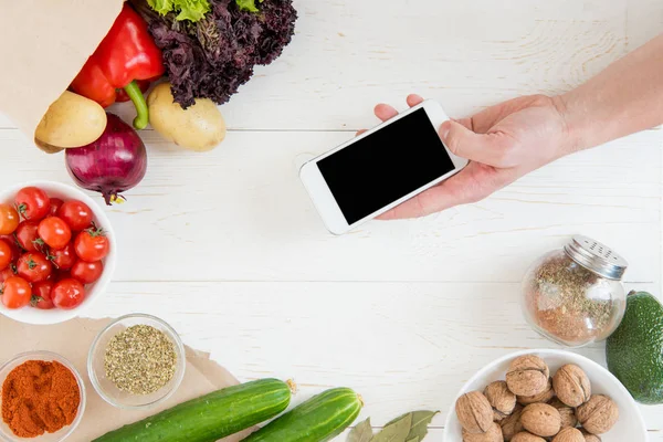 Смартфон за столом с овощами — стоковое фото