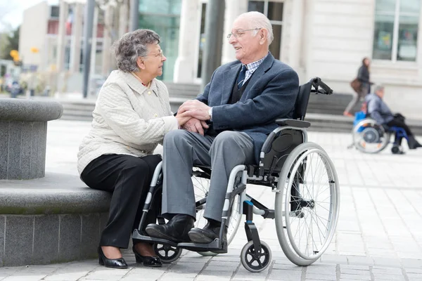 Старший на коляске с любящей женой рядом с ним — стоковое фото