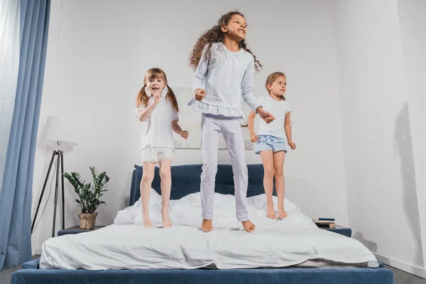 Многонациональное девочек, прыгать на кровати — стоковое фото