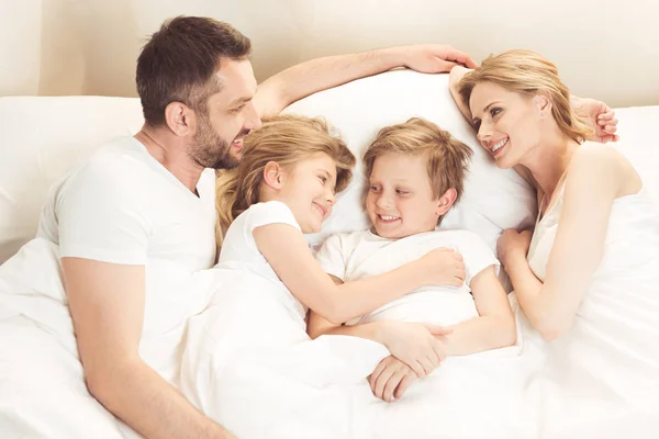 Счастливая кавказская семья, лежа в кровати — стоковое фото