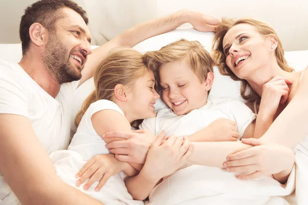 Счастливая кавказская семья, лежа в кровати — стоковое фото