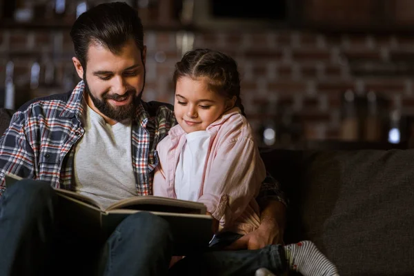 Счастливый Отец Дочерью Обниматься Диване Читать Книги Дому — стоковое фото