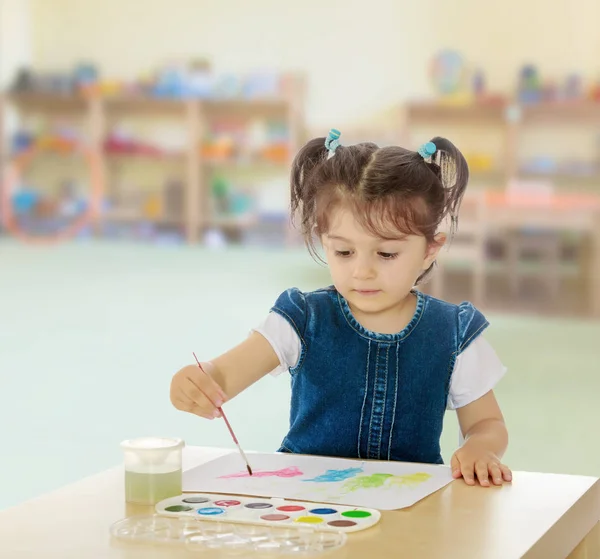 Маленькая девочка рисует акварели на столе — стоковое фото