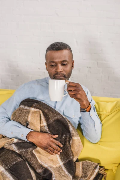 Senior African American Man Drinking Tea While Sitting Sofa Plaid — стоковое фото