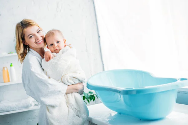 Smiling Mother Bathrobe Carrying Adorable Child Covered Towel Plastic Baby — стоковое фото