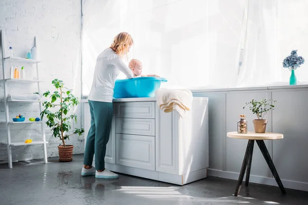 Mother Washing Her Little Child Plastic Baby Bathtub Home — стоковое фото