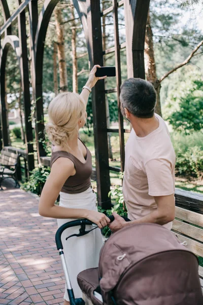 Back View Parents Taking Selfie Smartphone Baby Carriage Park — стоковое фото