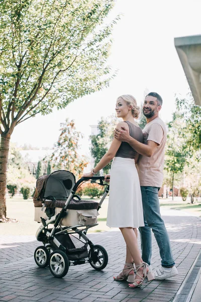 Happy Parents Cuddling Walking Baby Carriage Park — стоковое фото