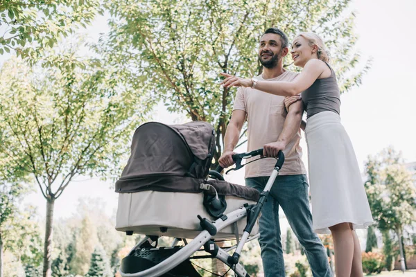 Happy Parents Walking Baby Carriage Park Wife Pointing Something Husband — стоковое фото