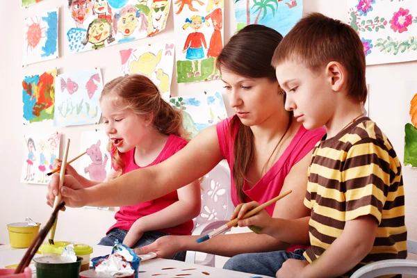 Ребенок с учителем рисования красками в игровой комнате — стоковое фото