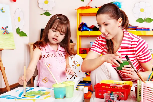 Ребенок с учителем рисования красками в игровой комнате — стоковое фото