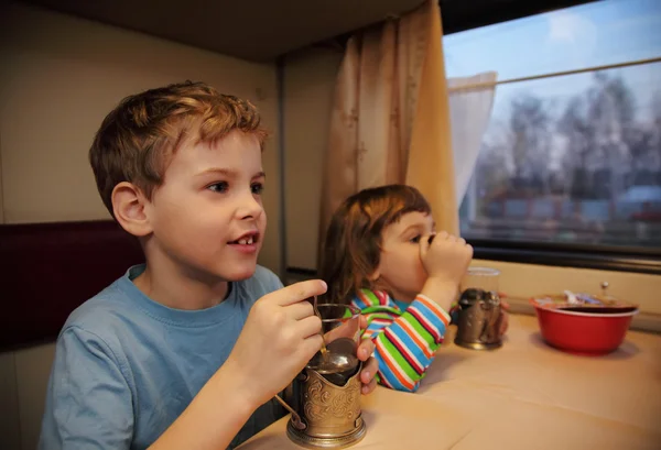 Двое детей пить чай из стекол в вагоне — стоковое фото
