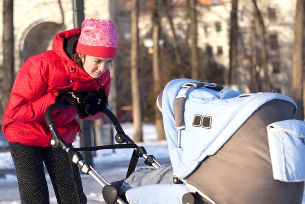 Молодая мама смотрит на ребенка в коляске — стоковое фото