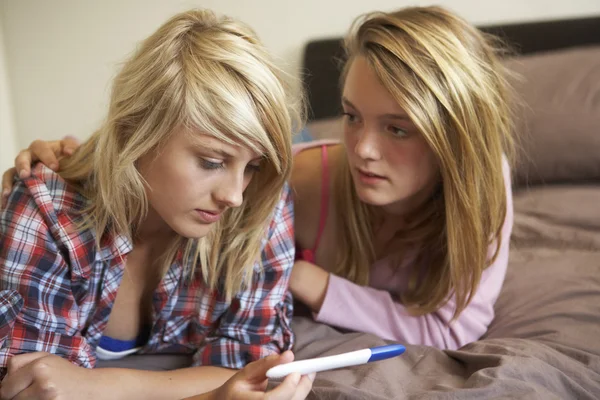 Две девочки-подростки, лежа на кровати, глядя на беременность тестирования комплект — стоковое фото