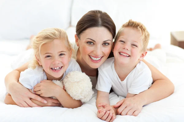 Счастливая мать и ее дети, лежащие на кровати — стоковое фото