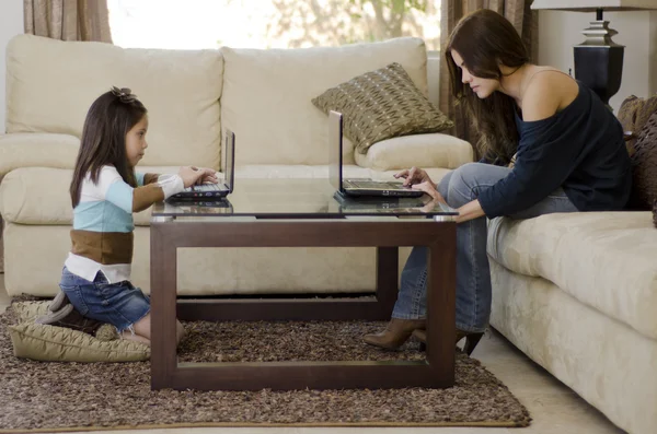 Молодая мать и дочь, используя свои ноутбуки в гостиной — стоковое фото