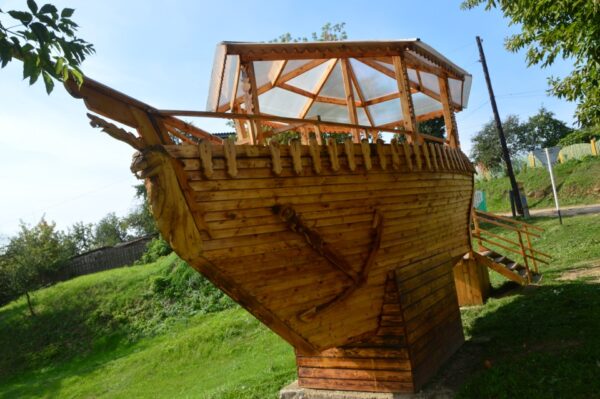 Плывущий по зелёному морю деревянный кораблик украсит собой любой садовый участок